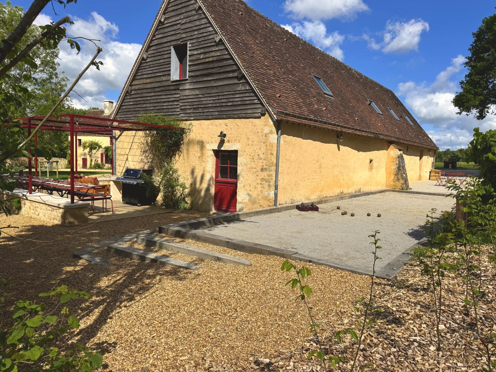 Terrain de pétanque le long de la grange en pierre aux portes rouges — Maison Oiserie